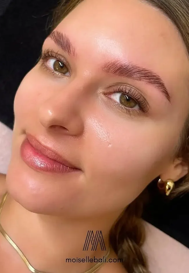 Close-up of a smiling client showcasing her flawless eyebrow lamination and tint results at Moiselle, a premium eyebrow studio Canggu.
