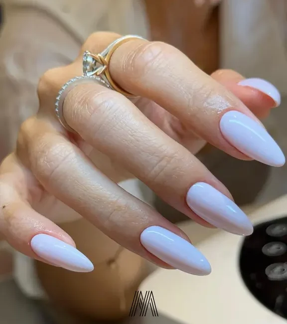 Close-up of a client's hand featuring a flawless milky white gel manicure on almond-shaped nails at Moiselle nail salon in Canggu, Bali