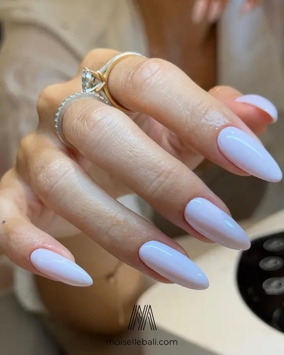 Close-up of a client's hand featuring a flawless milky white gel manicure on almond-shaped nails at Moiselle nail salon in Canggu, Bali