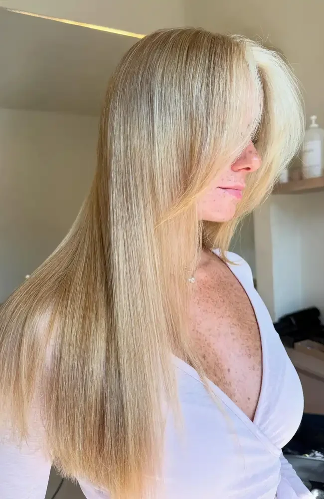 Side profile of a woman with long, sleek blonde hair and face-framing layers showcasing a fresh haircut at Moiselle hair studio Canggu, a premier hair salon Bali.