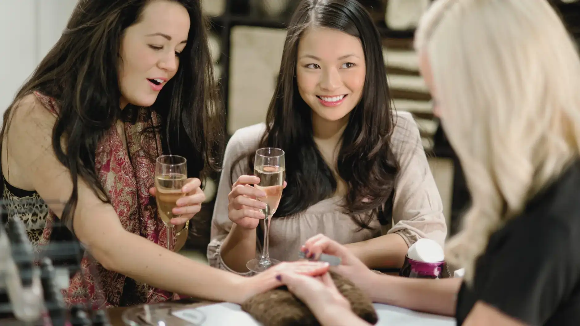 Two girls holding champagne glasses while enjoying a luxury manicure and pampering session at Moiselle salon Bali, a premium beauty lounge in Batu Bolong Canggu.